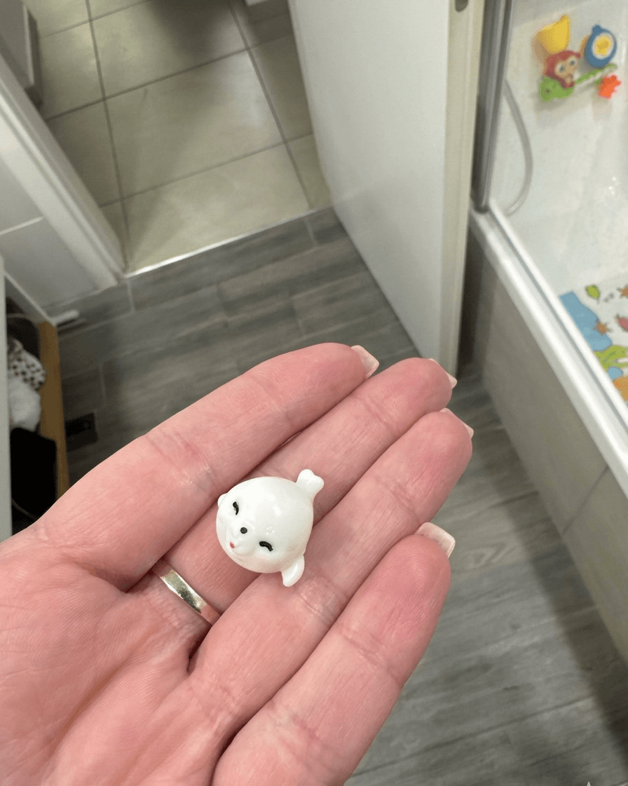 Small white figurine of a bear held in a hand with a kitchen background