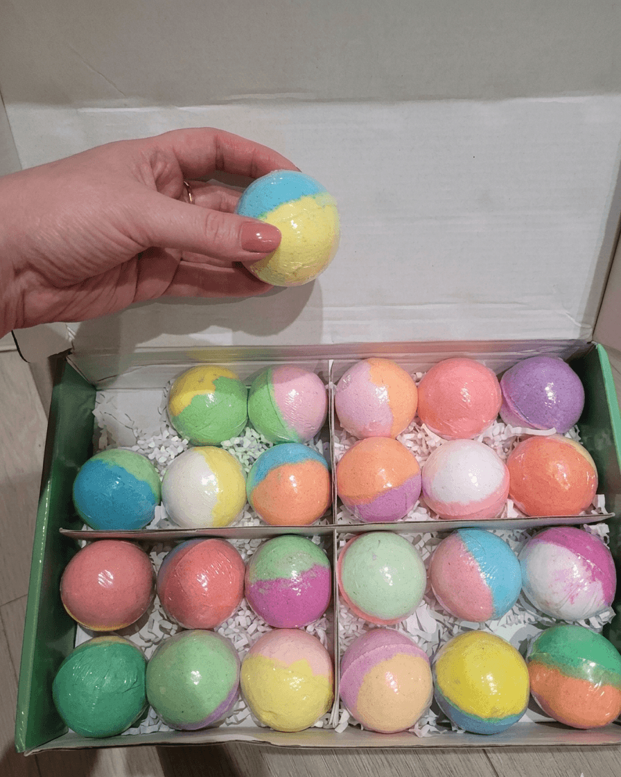 Colorful bath bombs in a box with a hand holding one above it.